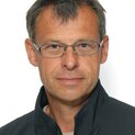 Ein Mann mit Brille schaut freundlich in die Kamera.