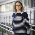 Eine Frau in einem blau-weißen Pullover schaut in die Kamera.