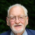 Ein Mann mit Brille und Bart lächelt in die Kamera.
