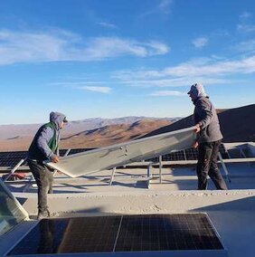 Bau der Rolf Chini Cerro Murphy-Sternwarte: Prof. Dr. Rolf Chini verlegt gemeinsam mit einer anderen Person Solarpanels auf dem Dach der Sternwarte. 
