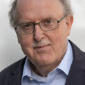 Mann mit Brille und OBerlippenbart lächelt.