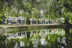 Nachhaltigkeitsforum 2024: Männer und Frauen laufen durch einen Park. 