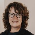 Eine Frau mit Brille lächelt in die Kamera.