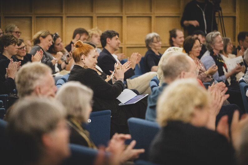 Ein Saal voller Menschen, die applaudieren.