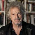 Ein Mann schaut in die Kamera. Im Hintergrund ist ein Bücherregal zu sehen.