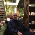 Mann mit Brille sitzt neben einem Bücherregal.