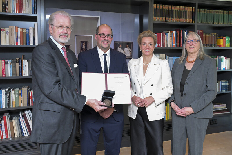Zwei Männer und zwei Frauen haben sich für ein Foto aufgestellt. Einer der Männer hält eine Urkunde ins Bild. 