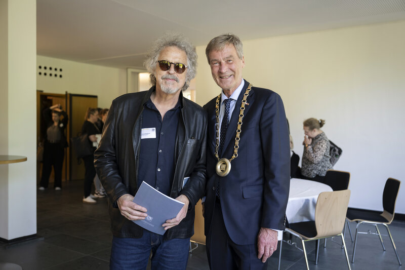 Zwei Männer haben sich für ein Foto aufgestellt. Einer von ihnen trägt eine Sonnenbrille.