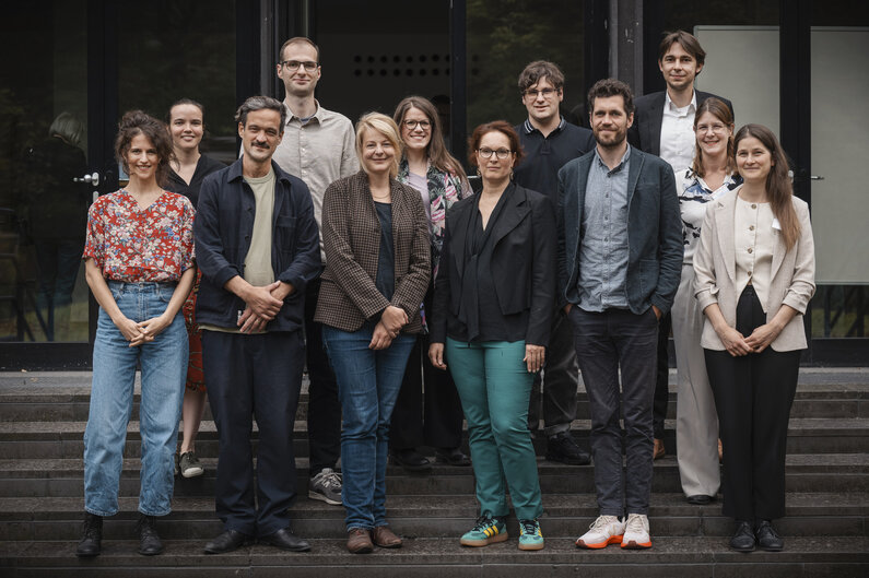 Frauen und Männer haben sich auf einer Treppe für ein Foto aufgestellt.