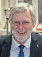 Mann mit Brille und Bart lacht in die Kamera.