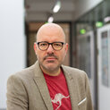 Ein Mann mit Brille schaut freundlich in die Kamera.