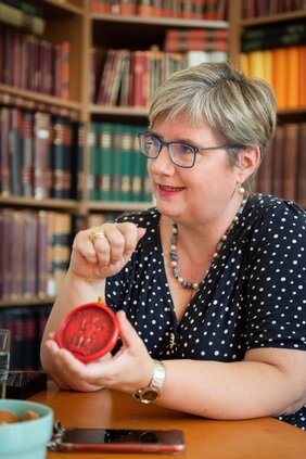 Porträtfoto Professorin Dr. Andrea Stieldorf. Die Historikerin hält ein rotes Wachssiegel in der Hand.