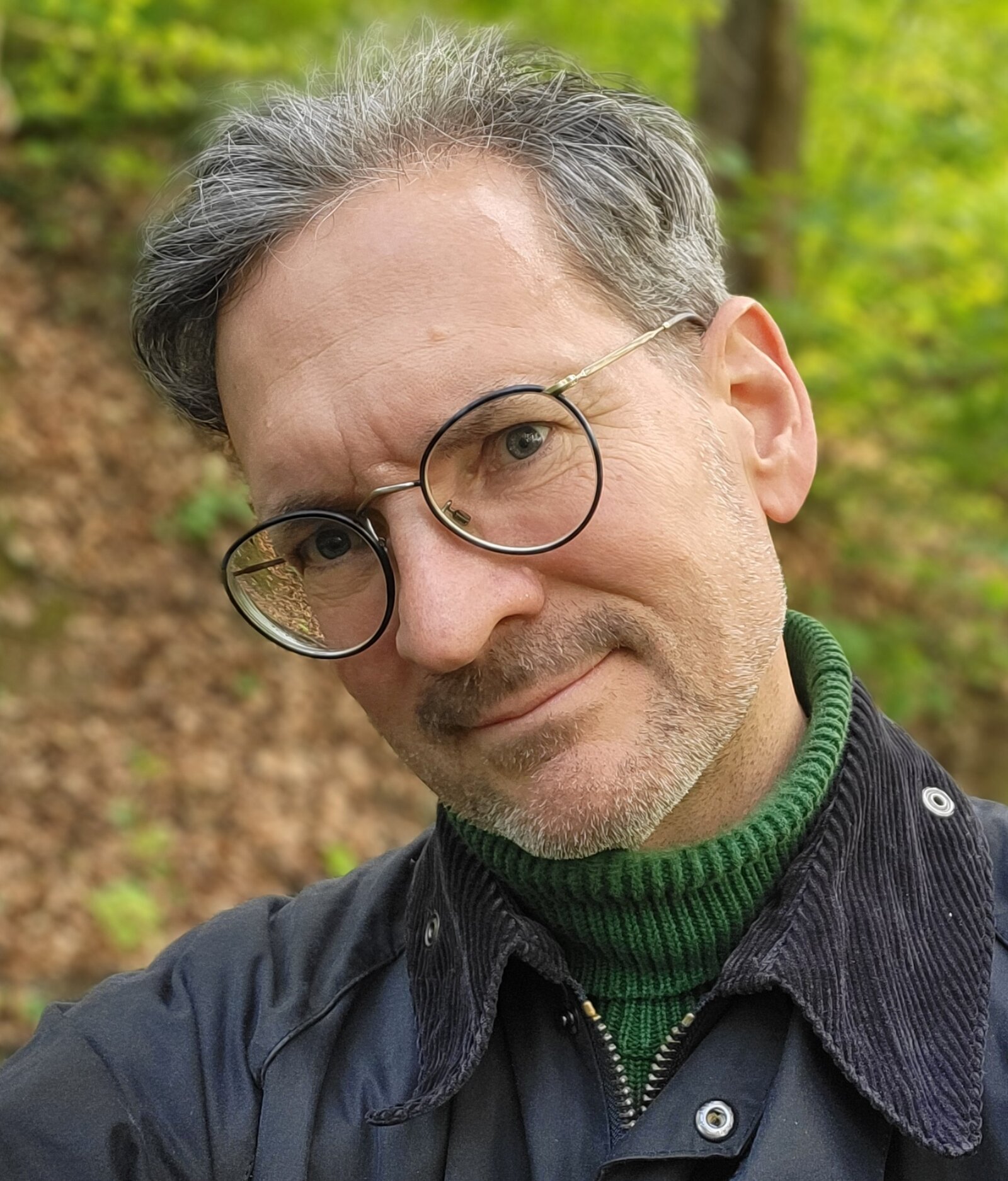 Mann mit Brille schaut mit genigtem Kopf in die Kamera.