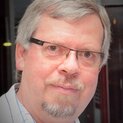 Ein Mann mit Brille schaut freundlich in die Kamera.