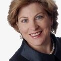Frau mit Perlenkette lächelt in die Kamera.