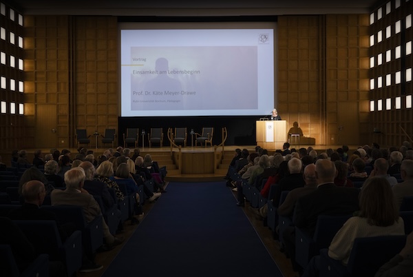 Ein gut gefüllter Veranstaltungssaal. Eine Frau hält einen Vortrag.