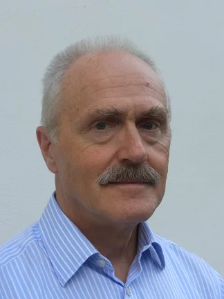 Mann mit Oberlippenbart lächelt.