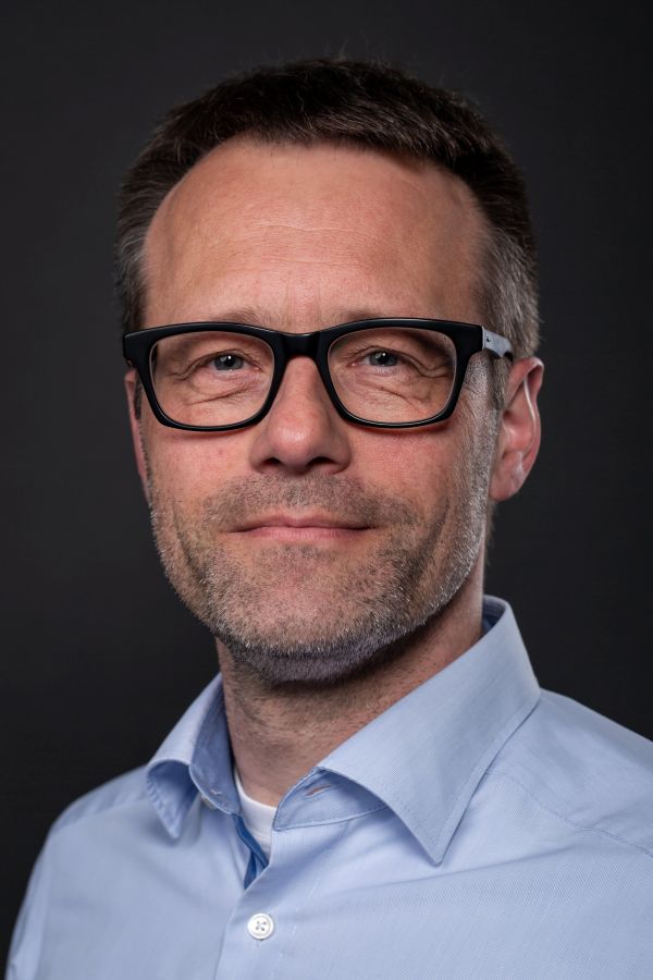 Ein Mann mit Brille und Bart schaut freundlich in die Kamera.