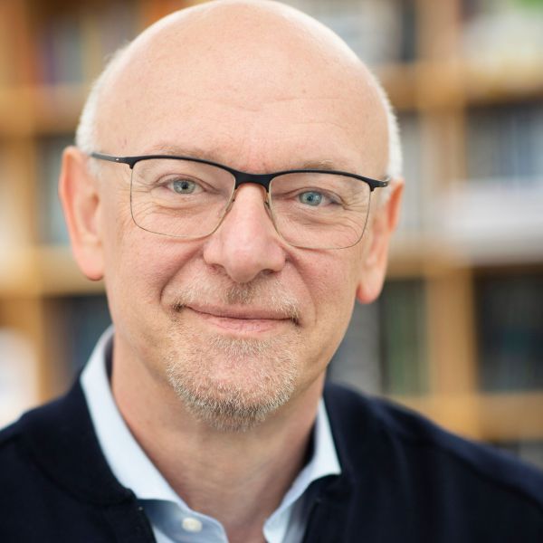 Ein Mann mit Brille schaut freundlich in die Kamera.