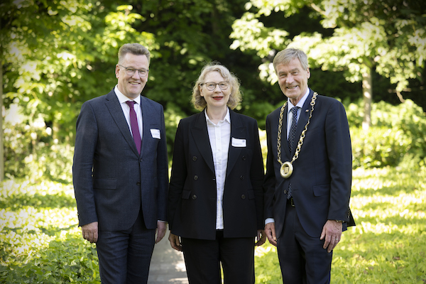 Eine Frau und zwei Männer haben sich in einem Park für ein Foto aufgestellt.