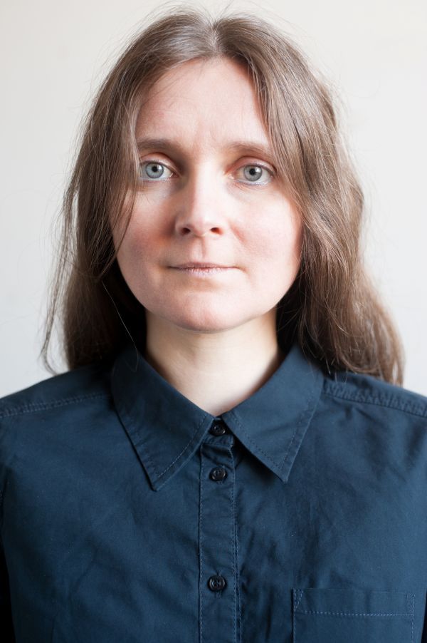 Eine Frau mit langem Haar trägt eine dunkle Bluse. Sie schaut freundlich in die Kamera.