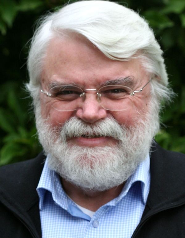 Ein Mann mit Vollbart und randloser Brille lächelt in die Kamera.