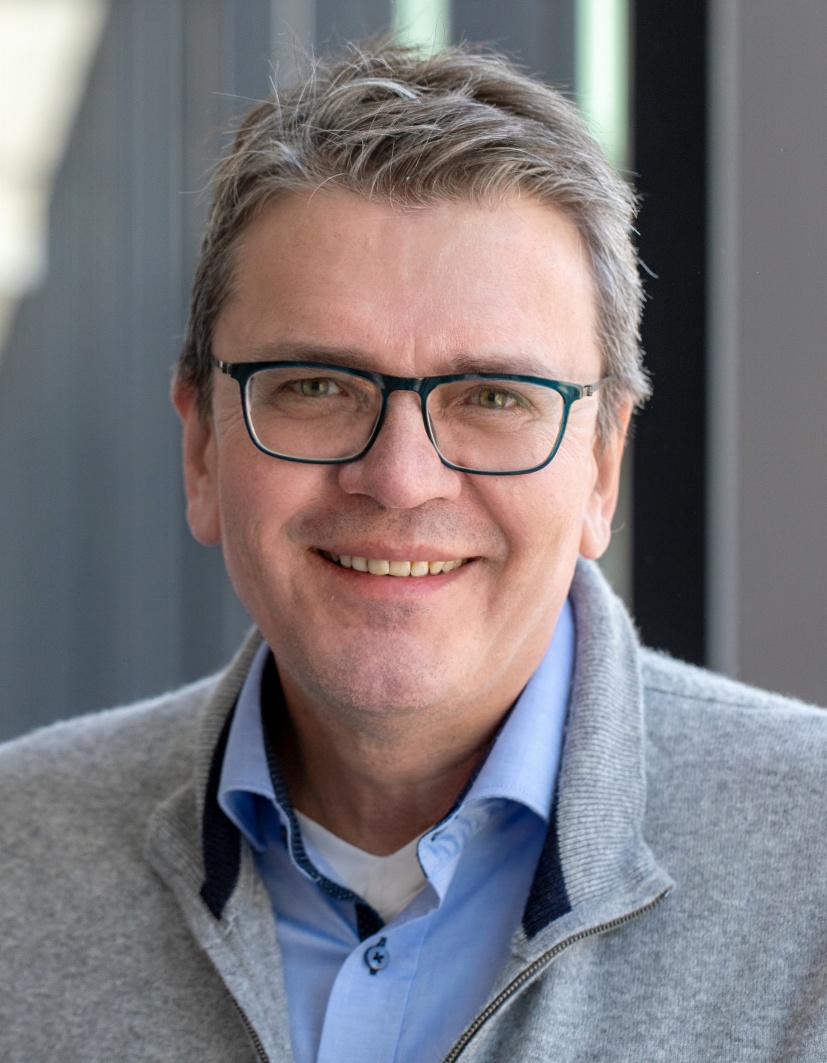 Ein Mann mit Brille lächelt strahlend in die Kamera.
